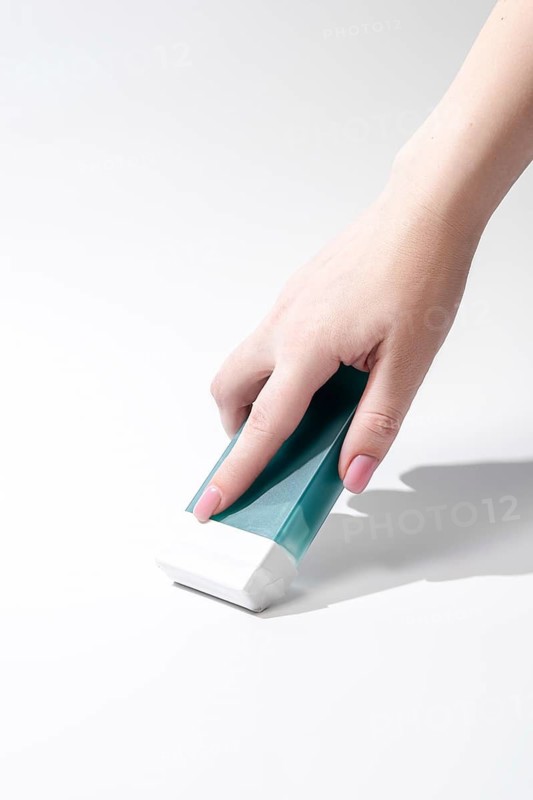 A hand applying roll on wax against a clean white background, showcasing the ease and efficiency of this hair removal method. Ideal for salon or personal use