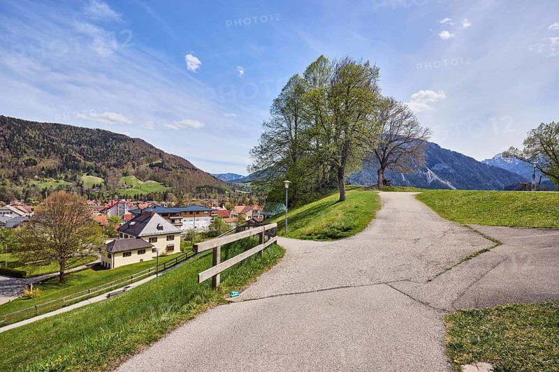 Mountain landscape, footpath, crossroads, wooden fence, mountains, hills, coniferous forest, village, meadows, trees with spring leaves, blue sky, cumulus clouds, cirrus clouds, cirrostratus clouds, Ruhpolding, Traunstein district, Bavaria, Germany