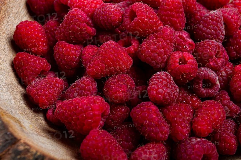 Fresh raspberries in a wooden bowl, food background, concept, food styling, on a dark table, top view, no people