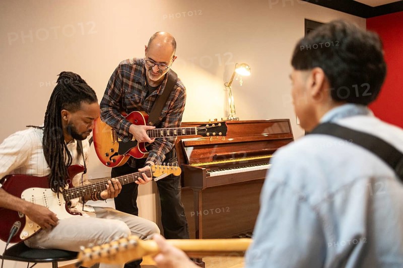 A diverse group of musicians jam in a cozy recording studio. Electric guitars, a piano, and warm lighting set the creative scene, fostering collaboration and artistic energy