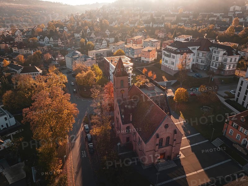 Church in the middle of a town in autumn light with surrounding trees and houses, Nagold, Black Forest, Germany