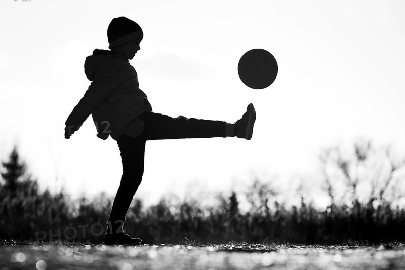Silhouette of young boy playing football