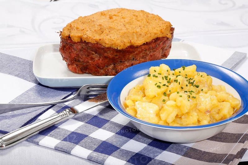 Swabian cuisine, Stuttgarter Leberkäs in a horseradish-mustard coating, Swabian potato salad, Leberkäse, meat loaf, mustard crust, grandmother's cooking, regional, home cooking, serving platter, cutlery, knife, fork, typical Swabian, traditional cuisine, food photography, studio, Germany