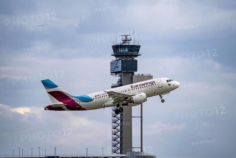 Eurowings Airbus A319-100 taking off at Düsseldorf International Airport, air traffic control tower