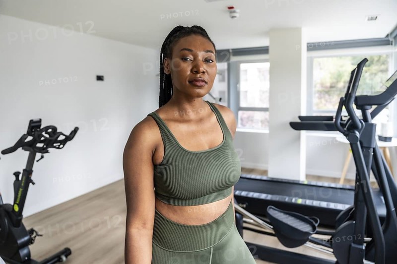 Businesswoman wearing sportswear standing in a hotel gym after a day of work, enjoying a moment of relaxation and wellness
