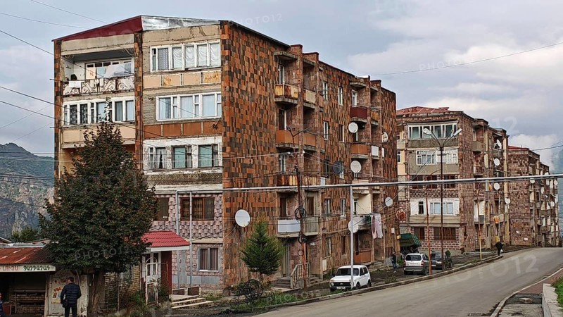 Row of old brick buildings with satellite dishes along the road, nostalgic charm, Armenia
