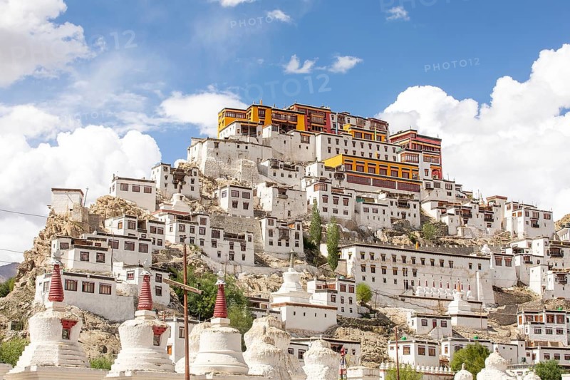 The majestic Thiksey Monastery stands against a backdrop of a bright blue sky in Ladakh, India. This Buddhist gompa is a striking example of traditional Tibetan architecture
