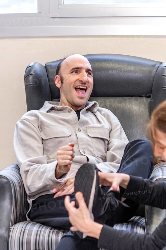 A man laughs joyfully while interacting with a caregiver in a mental health residence. The warm and supportive environment promotes healing and well-being, conveying a sense of connection