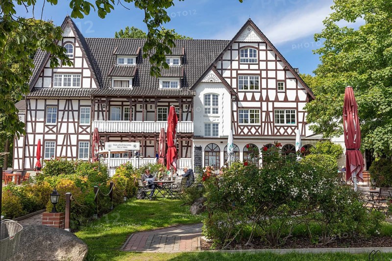 Half-timbered building with outdoor terrace and red parasol in the blooming summer garden, Rügen, Hiddensee