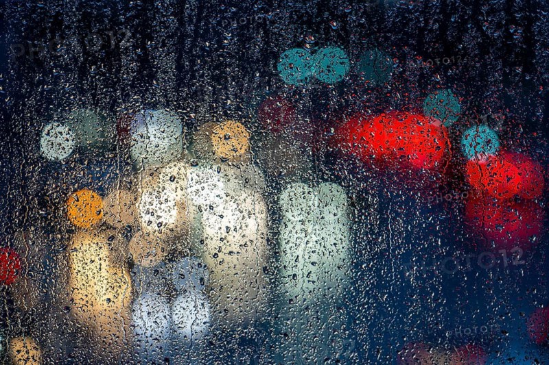Rainy weather, road traffic, raindrops on a window pane, behind, blurred, lights of vehicles on a rain-soaked road, traffic light, tail lights, headlights, symbolic image