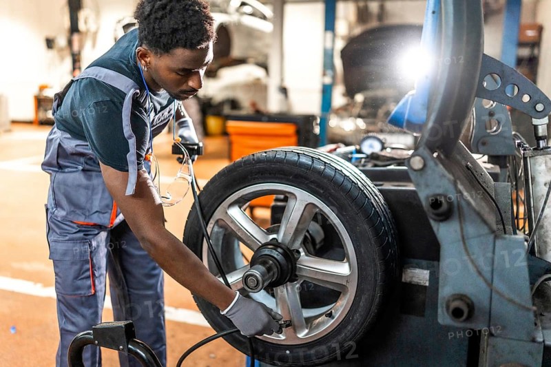 Professional mechanic balancing a car tire on advanced machinery in a modern auto repair shop, showcasing skill and precision in automotive service