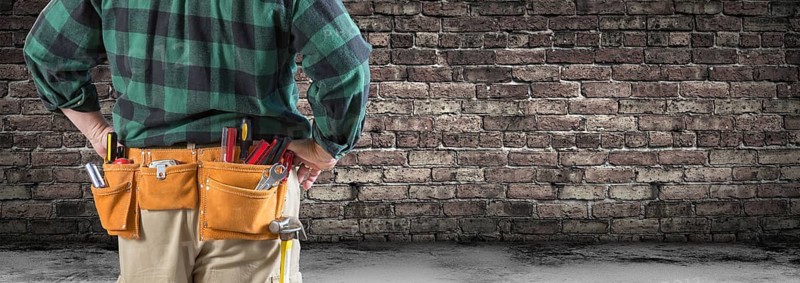 Contractor With Tool Belt Facing Aged Brick Wall Banner
