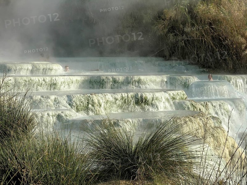 Warm sulphurous thermal springs, travertine waterfalls with clouds of water vapour, sinter, men bathing in sinter pools, Cascate del Mulino thermal baths, Saturnia, Manciano, Maremma, Province of Grosseto, Tuscany, Italy