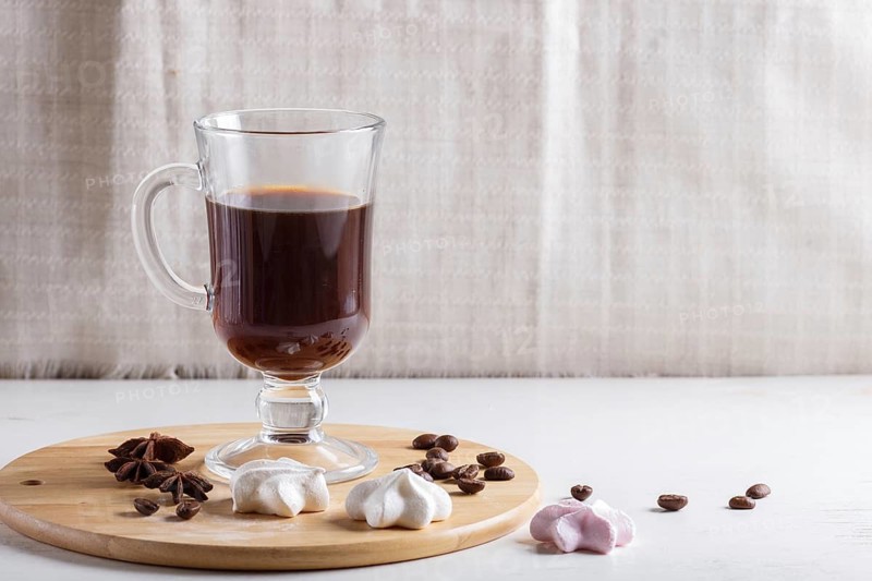 Glass cup of coffee with meringues on a wooden board on a white background. close up, copy space