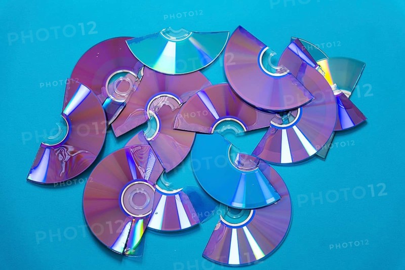 Top view of cut CDs and DVDs against a turquoise background