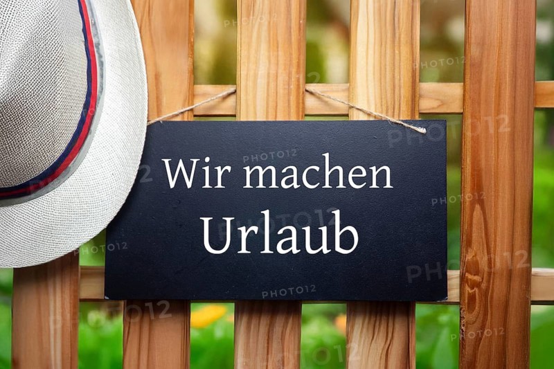 Company holidays Symbolic image: Sign with added text WIR MACHEN URLAUB on a wooden fence