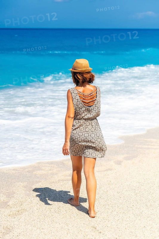 Woman walking along the sea at Megali Petra beach with turquoise water of Lefkada island, Ionian Sea, Greece