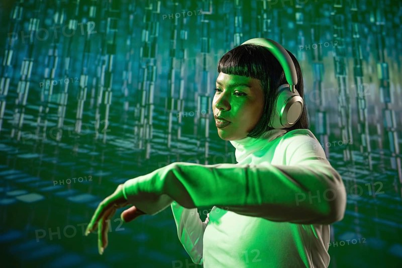 A futuristic Latin woman listens to music with headphones, immersed in technology. She stands in a glowing, digital environment, reflecting a blend of music and innovation