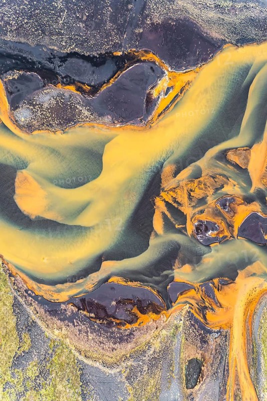 Stunning aerial photograph capturing the mesmerizing patterns and vibrant colors of golden rivers winding through the Icelandic landscape