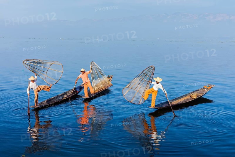 Myanmar travel attraction landmark, Traditional Burmese fishermen balancing with fishing net on boats at Inle lake in Myanmar famous for their distinctive one legged rowing style