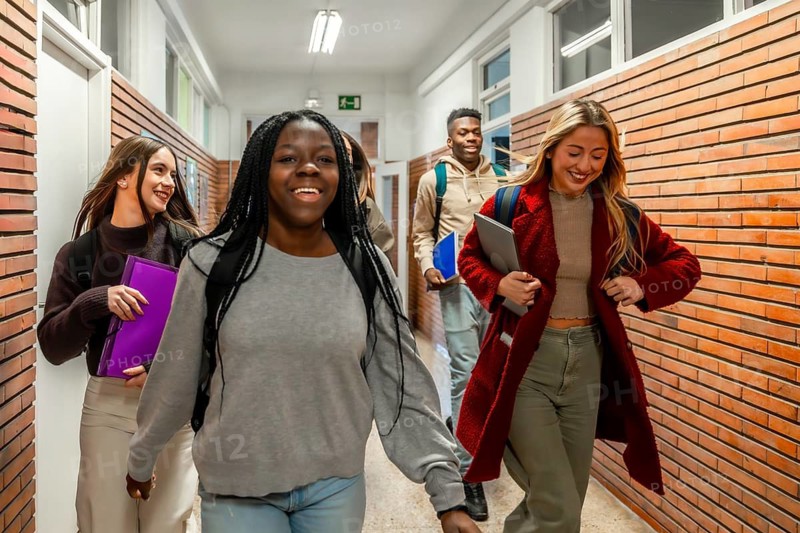 Cheerful multi ethnic university students walking together in a bustling school corridor, sharing laughter and enjoying their college experience