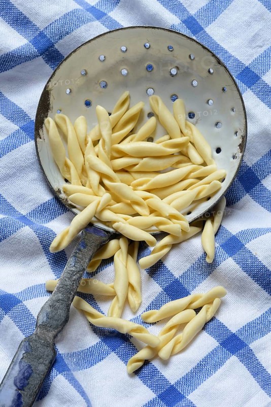 Strozzapreti, uncooked Italian pasta in a sieve, Italy