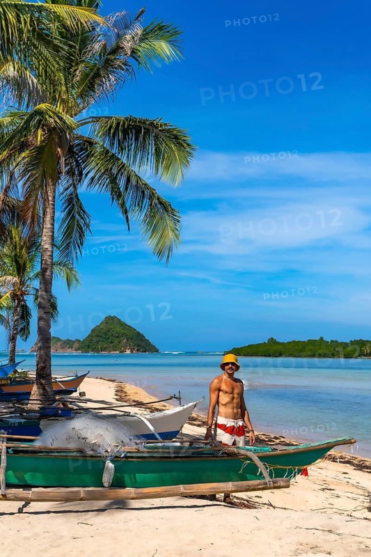 Filipino fisherman working near traditional bangka boats on idyllic lakdayan beach, coron island, philippines