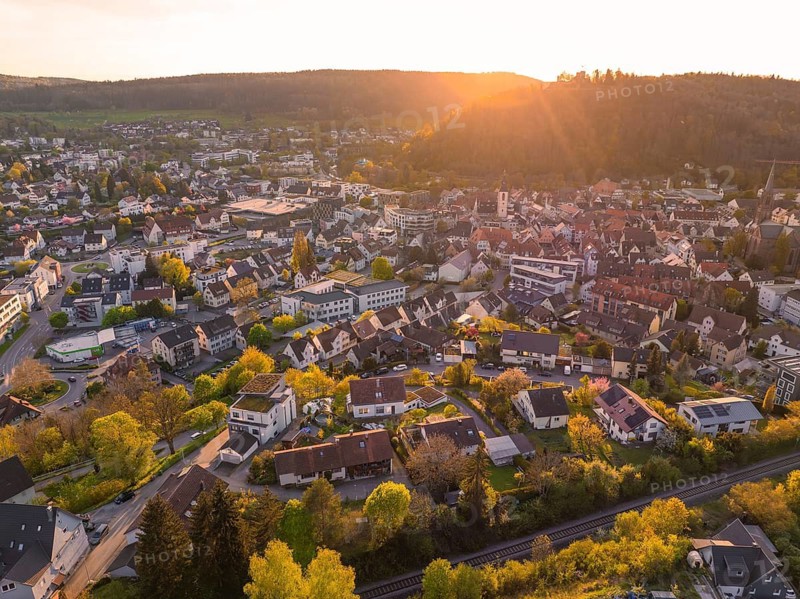 Urban landscape at sunset with many houses and green trees, surrounded by hills, Nagold, district of Calw, Germany