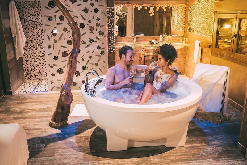 Happy interracial couple relaxed in the jacuzzi enjoying their self and drinking wine
