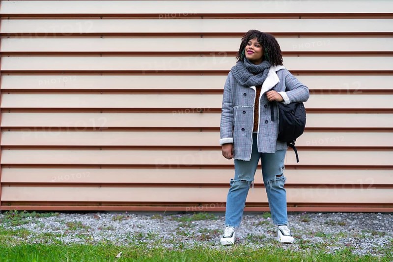 Portrait of black ethnic girl a gray wall in the university, with mochica from school on the back to school