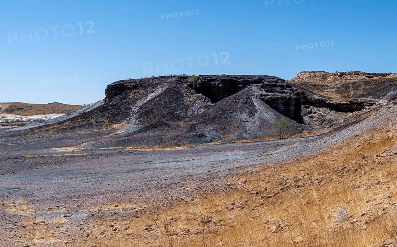 Dry landscape with yellow grass and black volcanic hills, Burnt Mountain, Damaraland, Kunene, Namibia