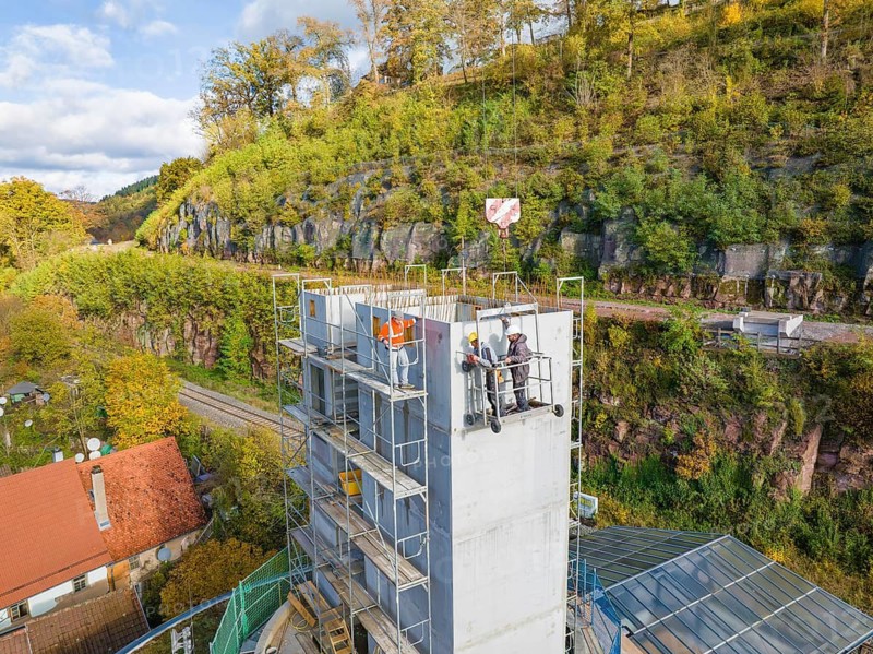 Workers on a towering building next to a hill, in the midst of autumnal nature, extension of the Calw railway station for the new track of the Hermann Hessebahn, Calw, Black Forest, Germany
