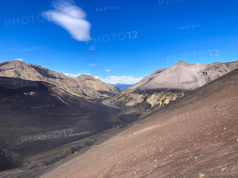 The lava scree slopes of the Achen Niyue volcano with a woman climbing up, Lanin National Park, Patagonia, Argentina