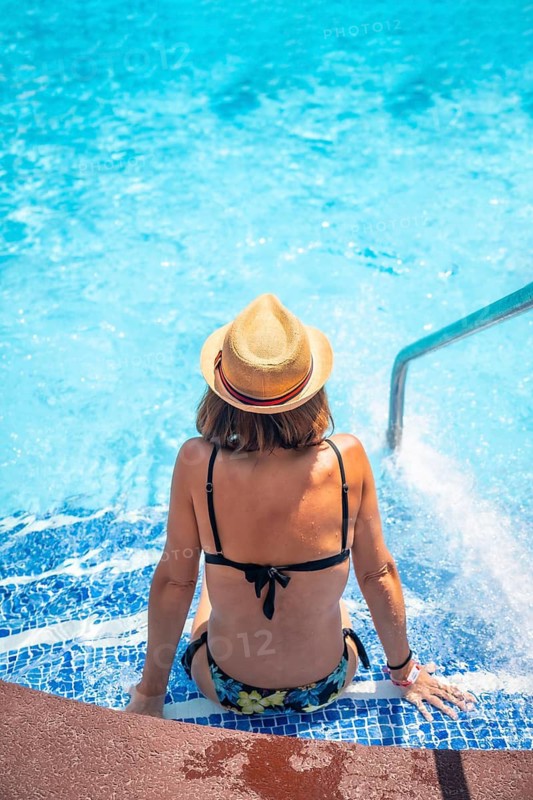 Young woman relaxing in pool at spa resort on vacation. Summer relaxing concept