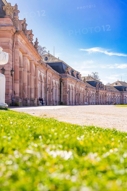Elegant historic palace with a view of a green meadow and blue sky in the sunshine, Schwetzingen Palace Gardens, Germany