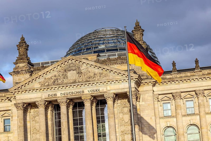 Reichstag building Berlin with German flags. Exterior view with dark clouds. Berlin, Germany