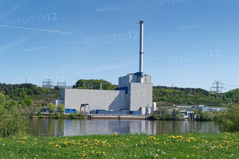 The decommissioned Krümmel nuclear power plant near Geesthacht on the Elbe, in front of it an early spring meadow with flowering dandelions. Geesthacht, Schleswig-Holstein, Germany
