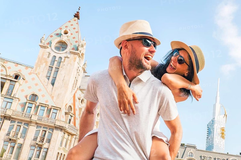 Beautiful young tourist couple having fun piggyback visiting Batumi Georgia. Tourists enjoying holiday in Europe in famous landmark - Vacation and happy lifestyle concept. Caucasus travel destination