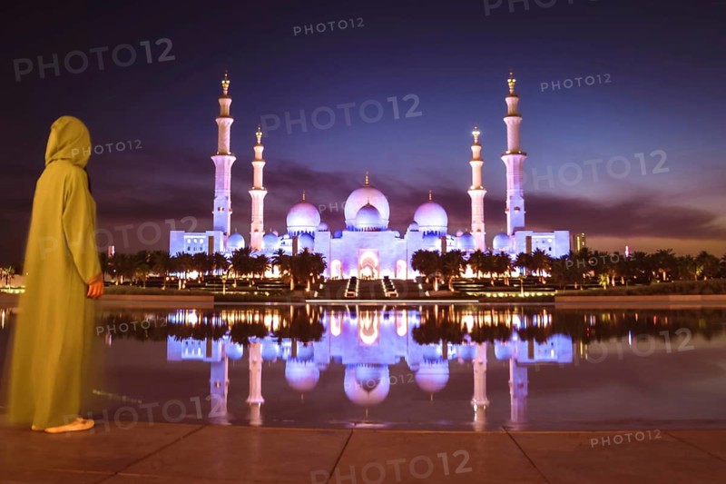 Close up Woman in traditional Arabic dress Abaya in Wahat Al Karama or Oasis of Dignity near Sheikh Zayed Grand Mosque in Abu Dhabi, showcasing cultural elegance, iconic Islamic architecture at sunset