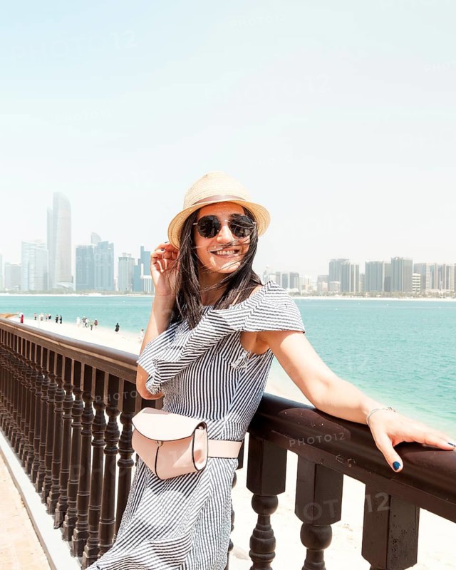 Young woman wear dress and straw hat visiting UAE capital Au Dhabi relax enjoy coastline view - Happy tourist walking sightseeing UAE - Travel and vacation lifestyle concept