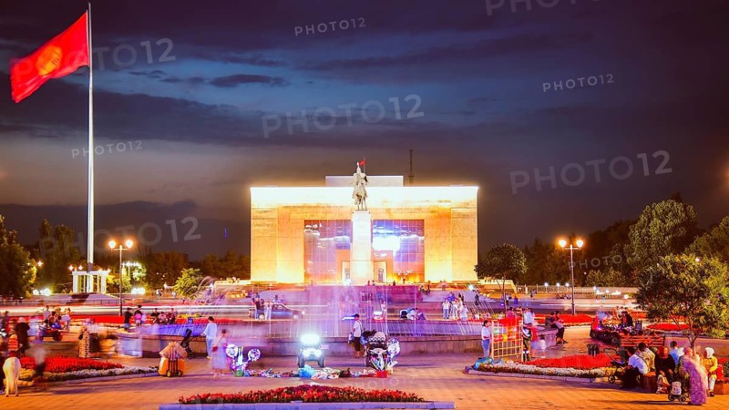Bishkek, Kyrgyzstan - 25th september, 2023: tourist visit Manas Statue in Ala-Too Square. State history museum and fountain with tourist in city square. Sunset blue hour sky background