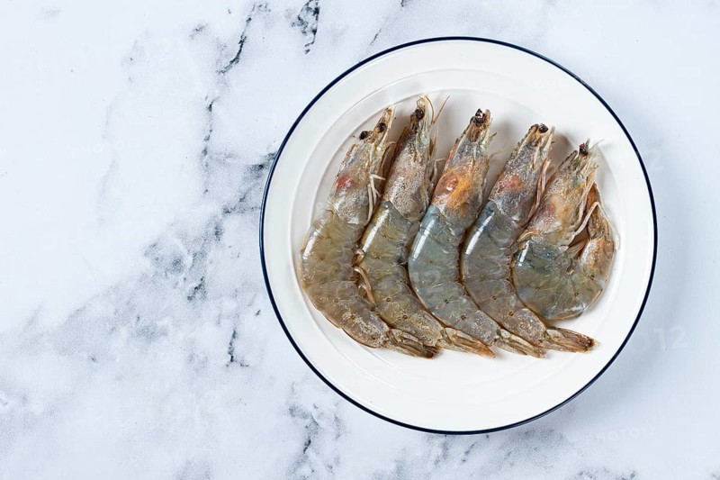 Fresh raw white-footed shrimp, tiger prawns vannamei, on a white plate