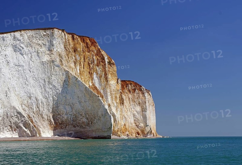 High white cliffs towering over the calm blue water, Beachy Head Cliffs, English Channel, Eastbourne, Sussex, England, United Kingdom