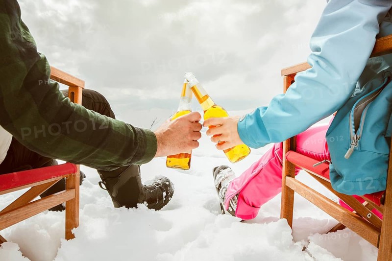 Couple relax sit on chairs in snowy ski resort with beer bottle, concept of leisure, winter holiday, relaxation, carefree lifestyle, freedom, cozy outdoor relaxation moment