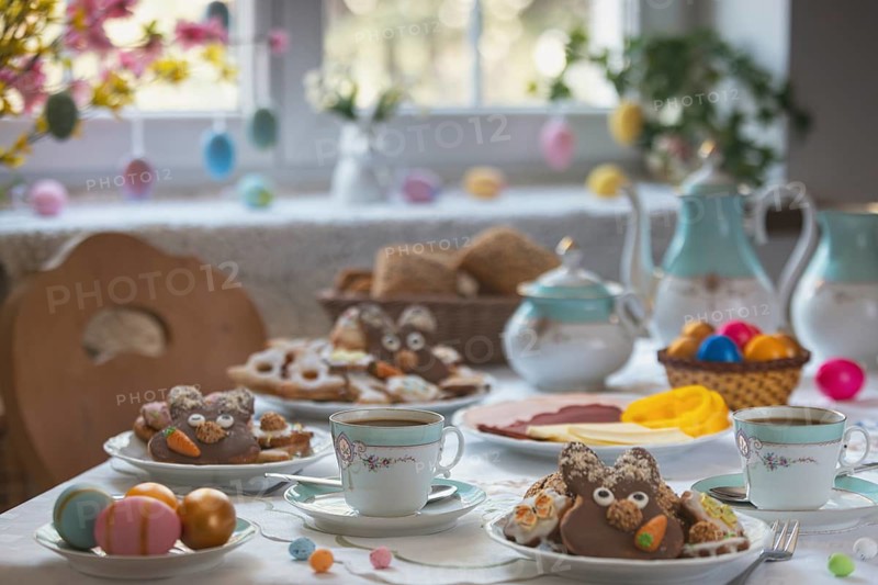Breakfast table with Easter eggs, cookies, pastries and a cold plate in front of a decorated window