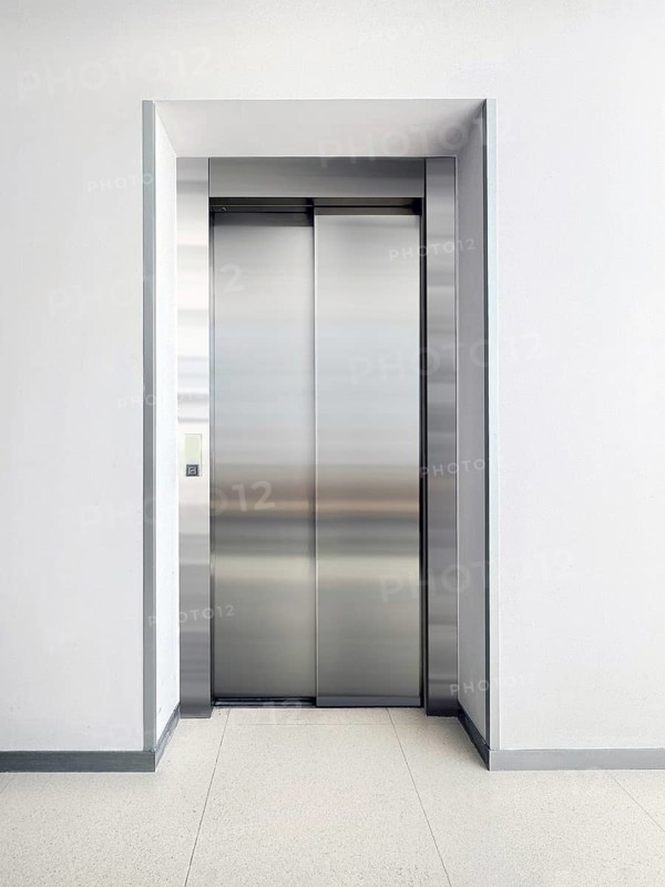 A sleek, stainless steel elevator door set in a modern hallway. The minimalist design and neutral colors create a clean, professional atmosphere. Ideal for architecture or interior concepts