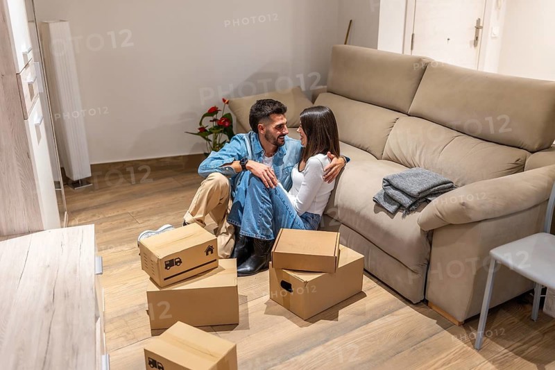 Young couple taking a break from unpacking, embracing amidst moving boxes in their new home, enjoying a moment of togetherness and excitement for their future