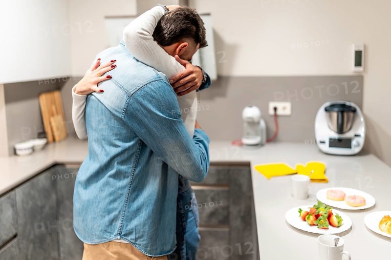 Romantic couple embracing in a cozy kitchen, enjoying a loving breakfast filled with pastries and strawberries, sharing tender moments together