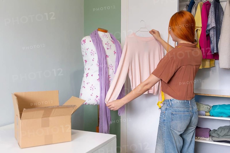 A young woman organizes her closet and prepares to sell clothes online She carefully selects garments, highlighting sustainable fashion and organizing her wardrobe