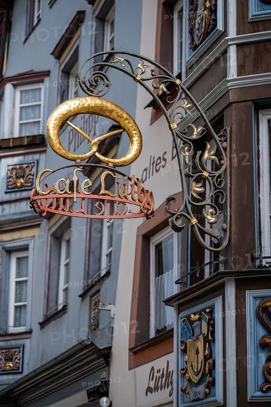 Traditional guild symbol for baking crafts, nose sign with the lettering Cafe Lüthy and a golden pretzel in the historic old town of Rottweil, Rottweil district, Baden-Württemberg, Germany